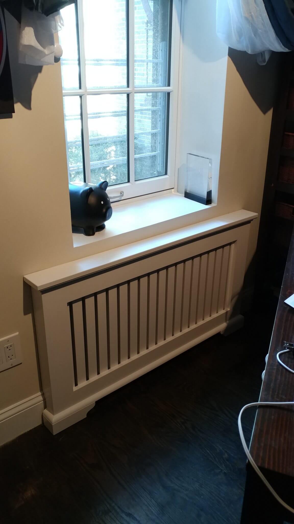 Wood radiator cover in white with flush installation under a window.