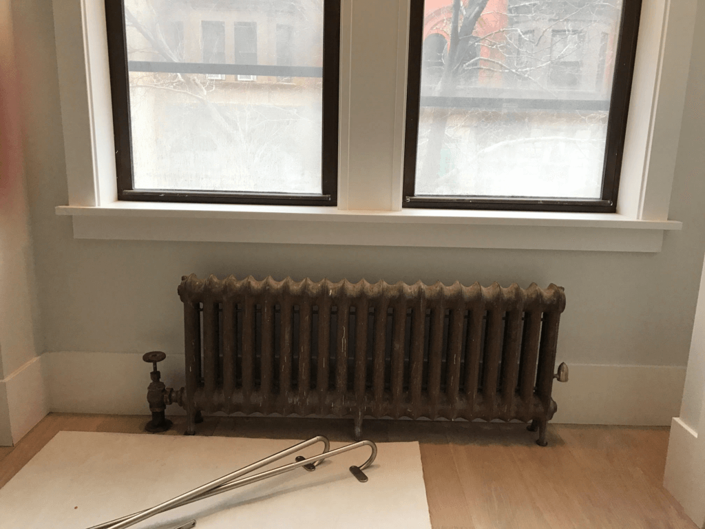 Before installation shows  a big old dirty cast iron radiator.  But very efficient at heating the kids room.